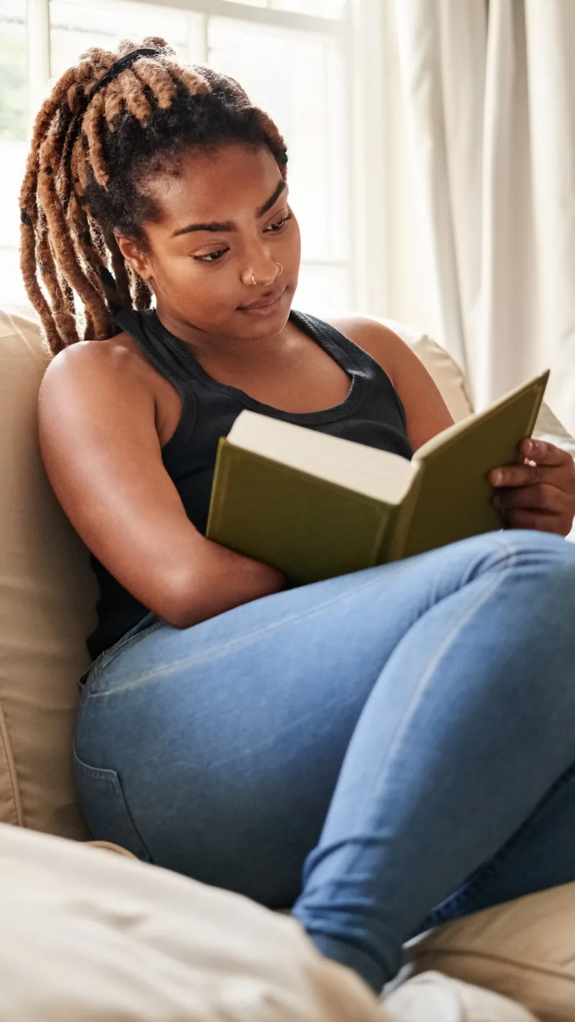Woman reading a book on the couch.