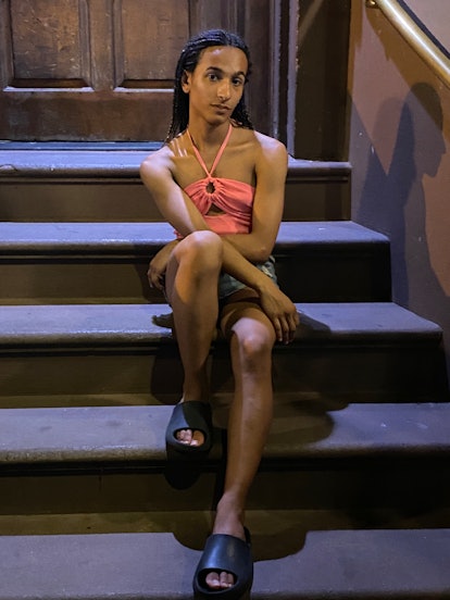 Avery Vyvyan Avanti, a trans person sitting on stairs wearing an orange dress