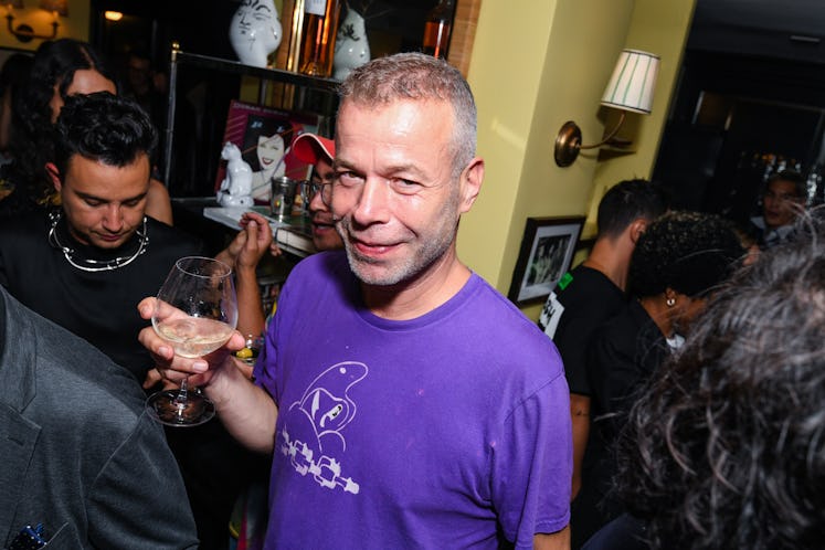 Wolfgang Tillsmans wearing a purple t-shirt and holding a wine glass