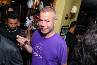 Wolfgang Tillsmans wearing a purple t-shirt and holding a wine glass