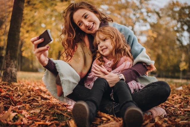 A woman and her daughter take a fall selfie.