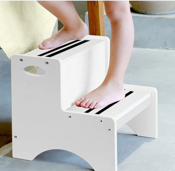 Toddler standing on white step stool with black nonslip lines