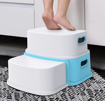 Toddler standing on a white and blue step stool