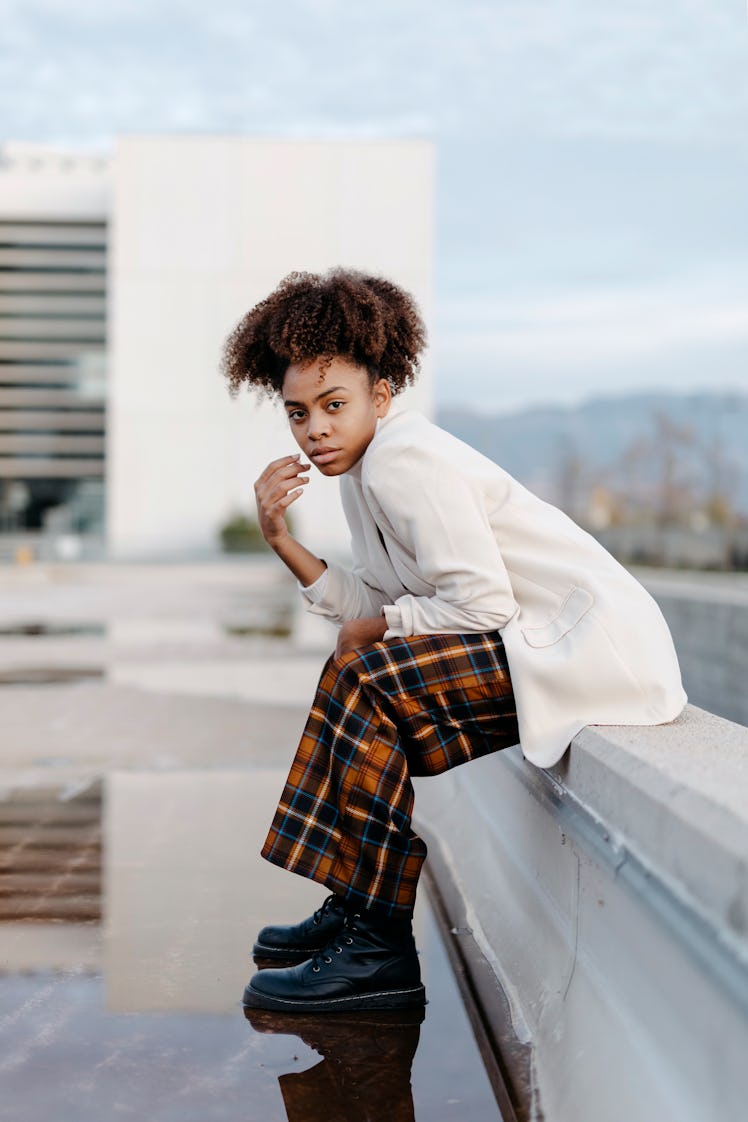 Young woman sitting on retaining wall over puddle against building during the September 2022 full Ha...