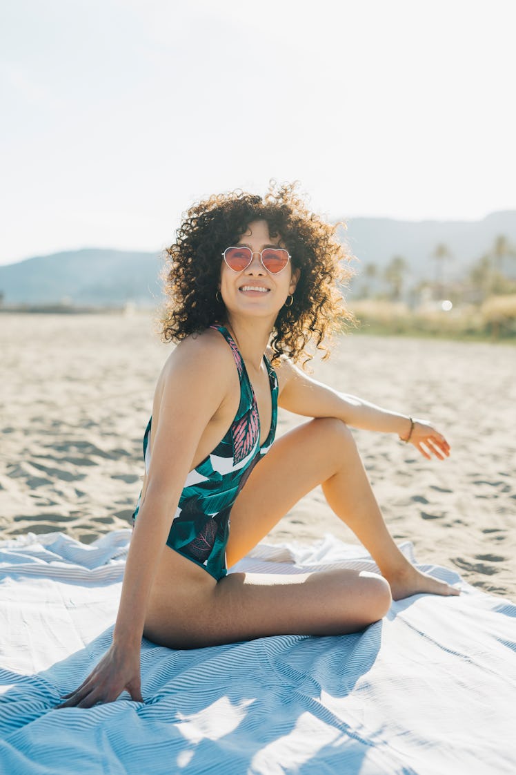 Young woman having a sunbath on the beach during the September 2022 full Harvest Moon, which will af...