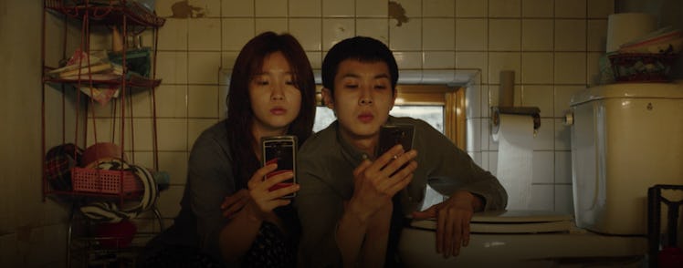 Siblings Ki-jung and Ki-woo crouch in semi-basement