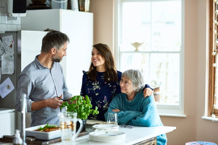 Man in kitchen talking to older woman and younger woman
