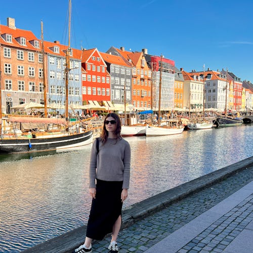 Courtney Falsey wearing a black skirt and a grey shirt while posing in Nyhavn 