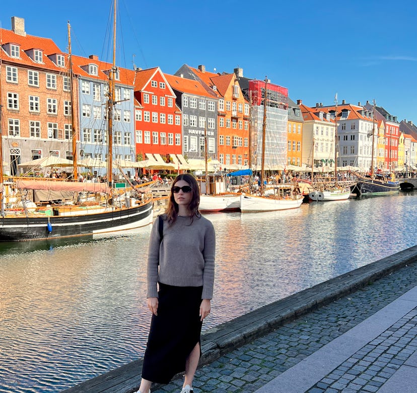 Courtney Falsey wearing a black skirt and a grey shirt while posing in Nyhavn