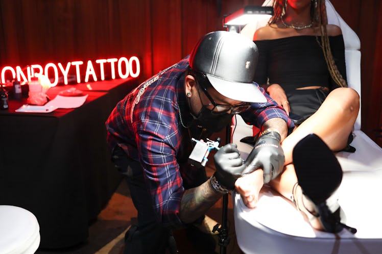Celebrity tattoo artist Jonboy tattooing a guest at one of the New York Fashion Week Spring 2023 Par...