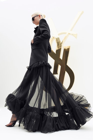 A blonde model walking in a black Saint Laurent dress