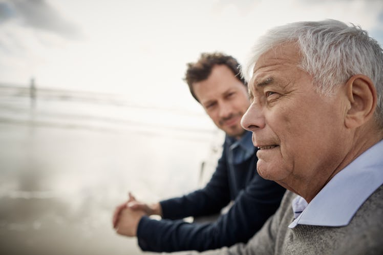Adult son and elderly father sitting together on a bench