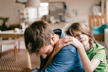 A sad dad being consoled by his son at home.