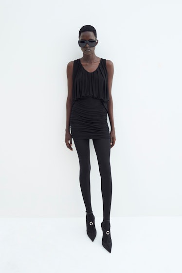 A female model posing in black Saint Laurent leggings and mini dress