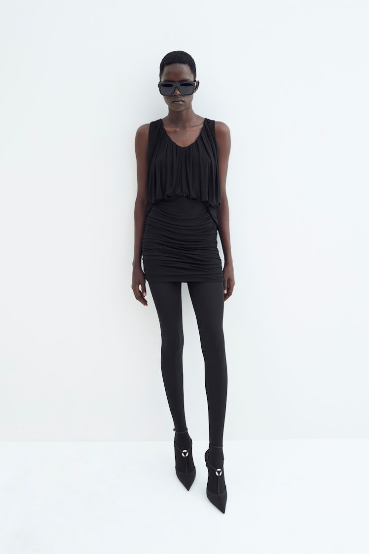 A female model posing in black Saint Laurent leggings and mini dress