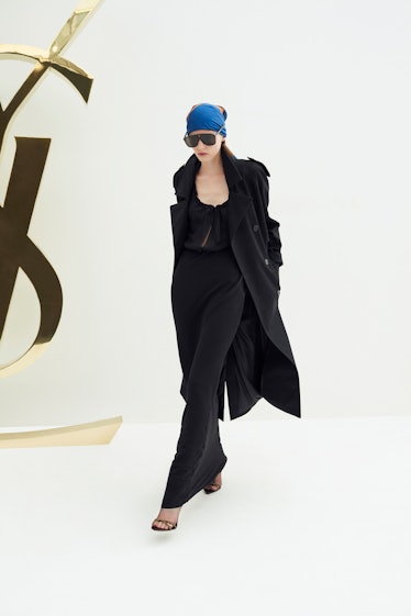 A female model posing in a black Saint Laurent coat and dress combination