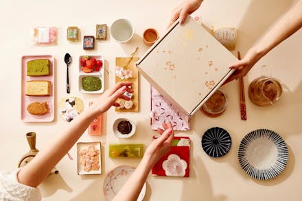 View of Sakuraco snack box, with the arms of one person gifting it to another