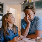 A daughter and father talking at a table at home.