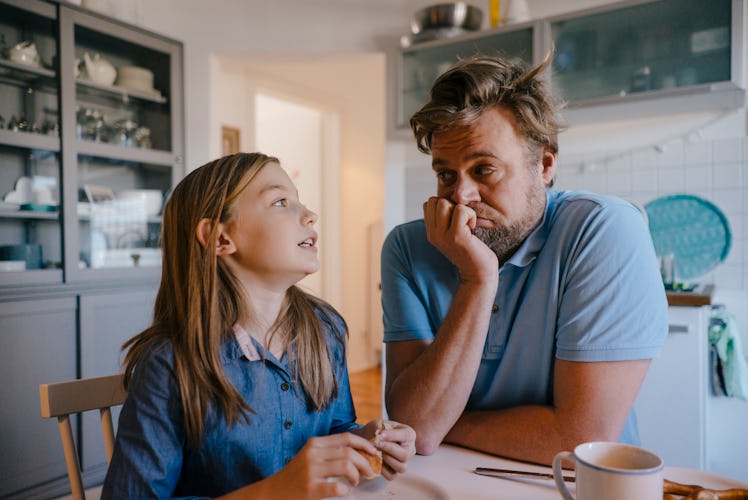 A daughter and father talking at a table at home.