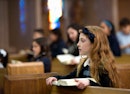 在天主教宗教仪式上坐在教堂长凳上的女孩。