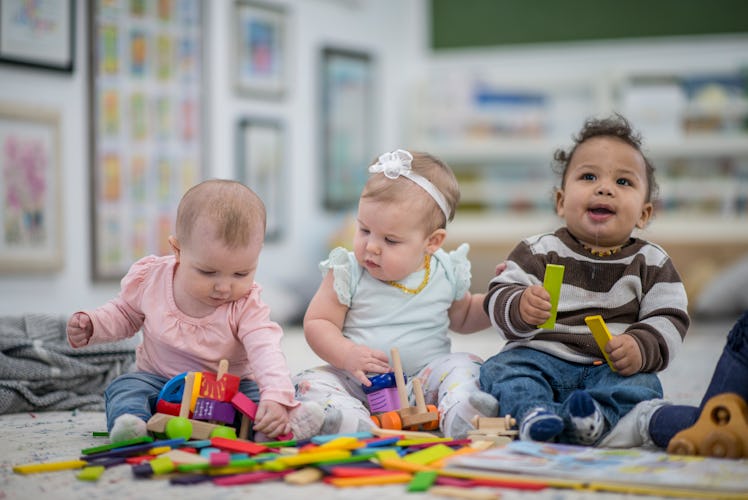 Three babies sitting up and playing with toys.