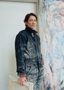 A portrait of Francesca Mollett in front of one of her works in her studio in London