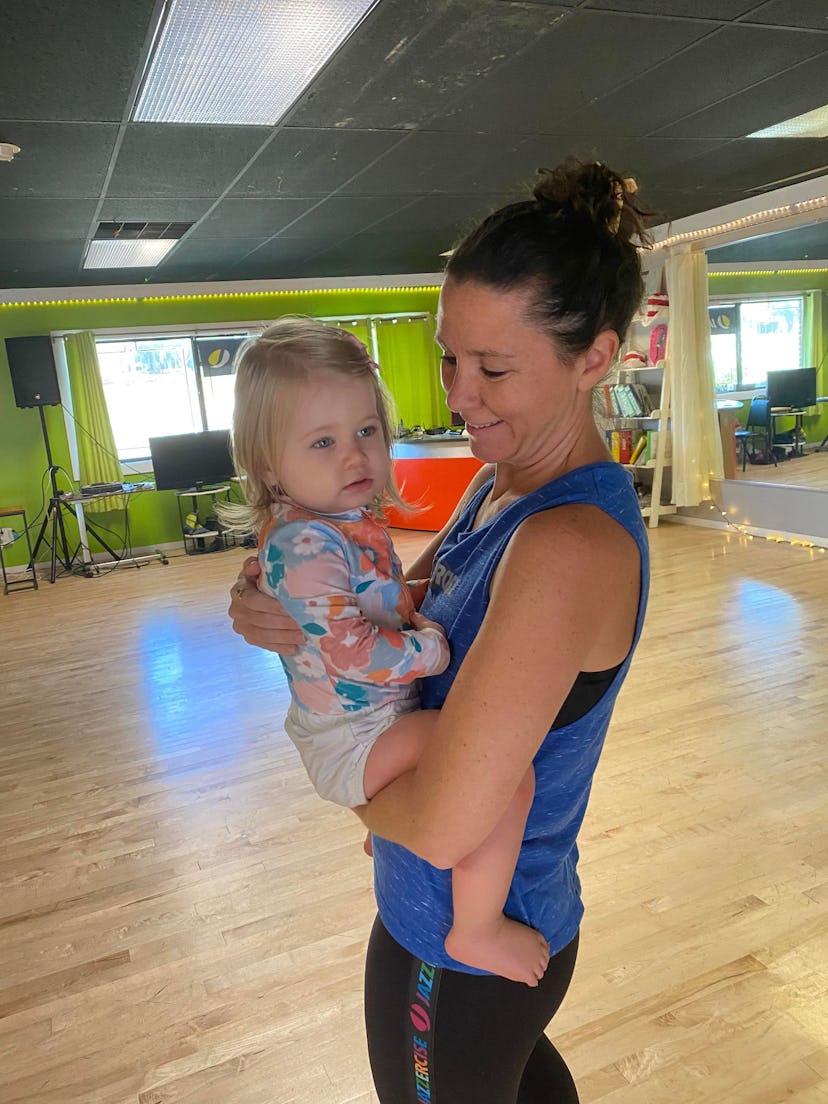Tiffany holding her daughter in an exercise studio.