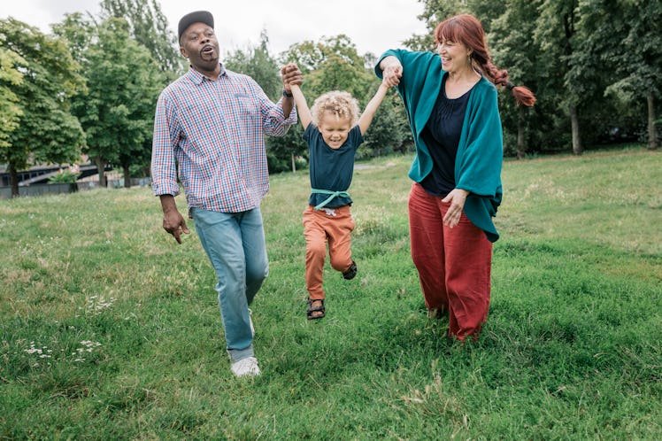 Two older parents swinging their child by his hands.
