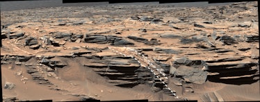 A jagged terrain view of Mars. On the bottom shelf of land are two annotated white lines with dashes...
