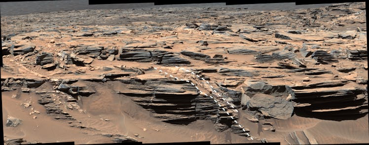 A jagged terrain view of Mars. On the bottom shelf of land are two annotated white lines with dashes...