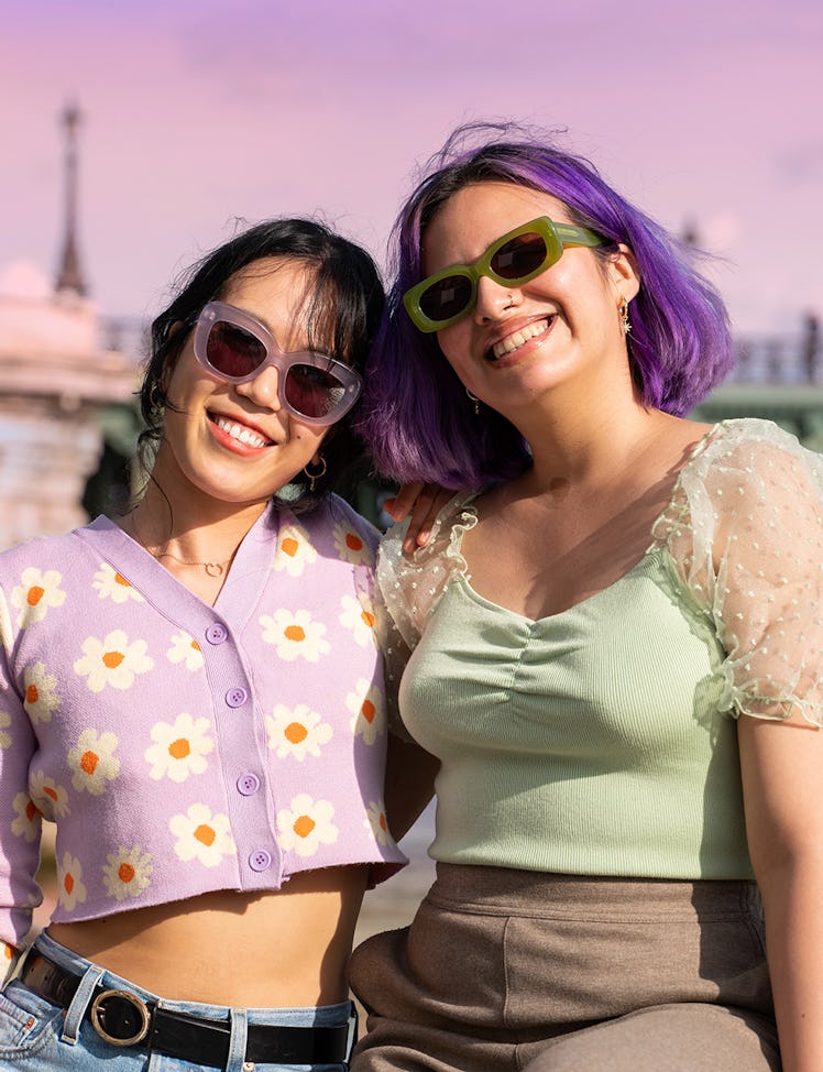 Two young women smiling on a trip after learning how to travel on a budget after college.