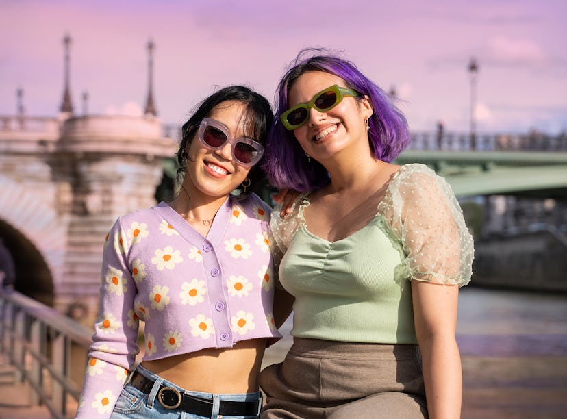 Two young women smiling on a trip after learning how to travel on a budget after college.