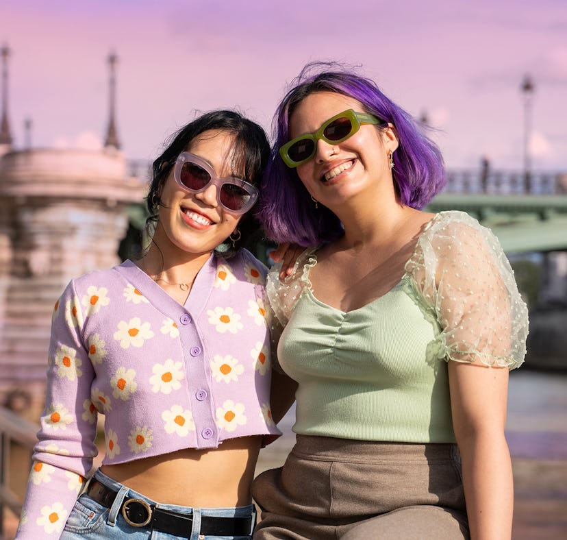 Two young women smiling on a trip after learning how to travel on a budget after college.