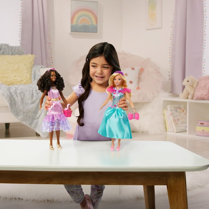 A child playing with two My First Barbie dolls, which are larger and softer than the traditional Bar...