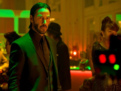 Keanu Reeves stands under a green light as John Wick