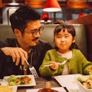 A dad and daughter eating in a restaurant.