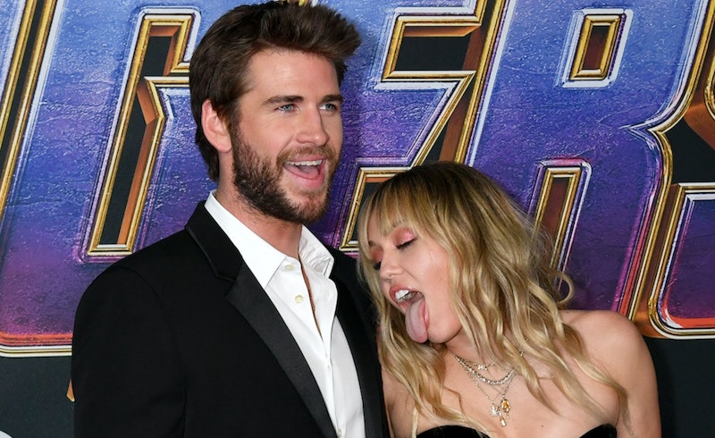 miley cyrus licks liam hemsworth on the red carpet, causing liam to tell her to "behave'