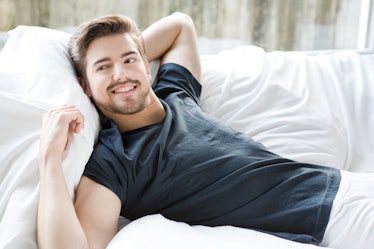 A man in underwear smiling on his bed.