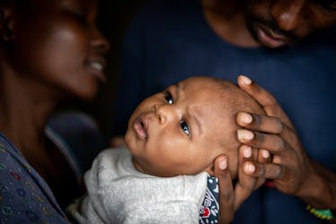 一对父母抱着他们的孩子,孩子的头型很奇怪。