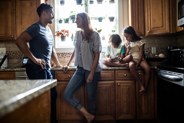 Couple talking in kitchen while kids look on
