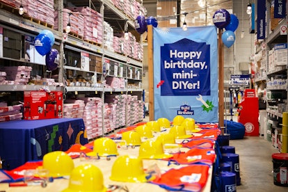 A table set up for a Build a Birthday party at Lowe's with construction hats, aprons, and DIY activi...