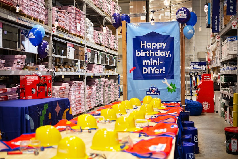 A table set up for a Build a Birthday party at Lowe's with construction hats, aprons, and DIY activi...