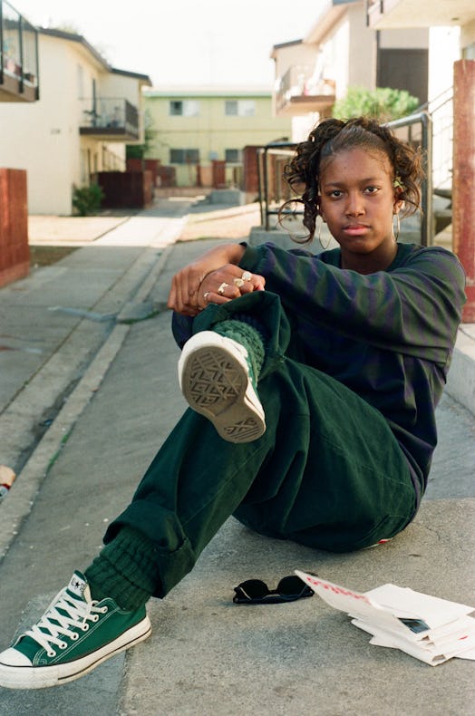 a picture of a young woman sitting with her legs crossed and her hands over her knees