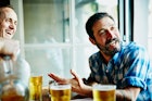 男人边喝啤酒边和朋友聊天。