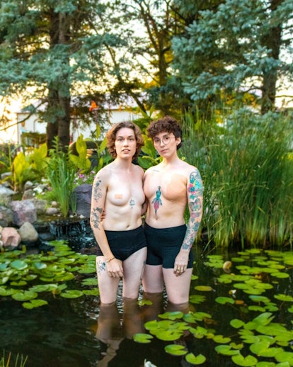 lesbian non-binary couple col and ari pose topless in a pond