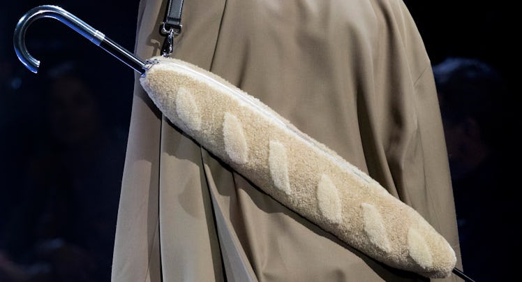 a model seen from behind wearing an umbrella strapped across his back that's encased in a shearling ...