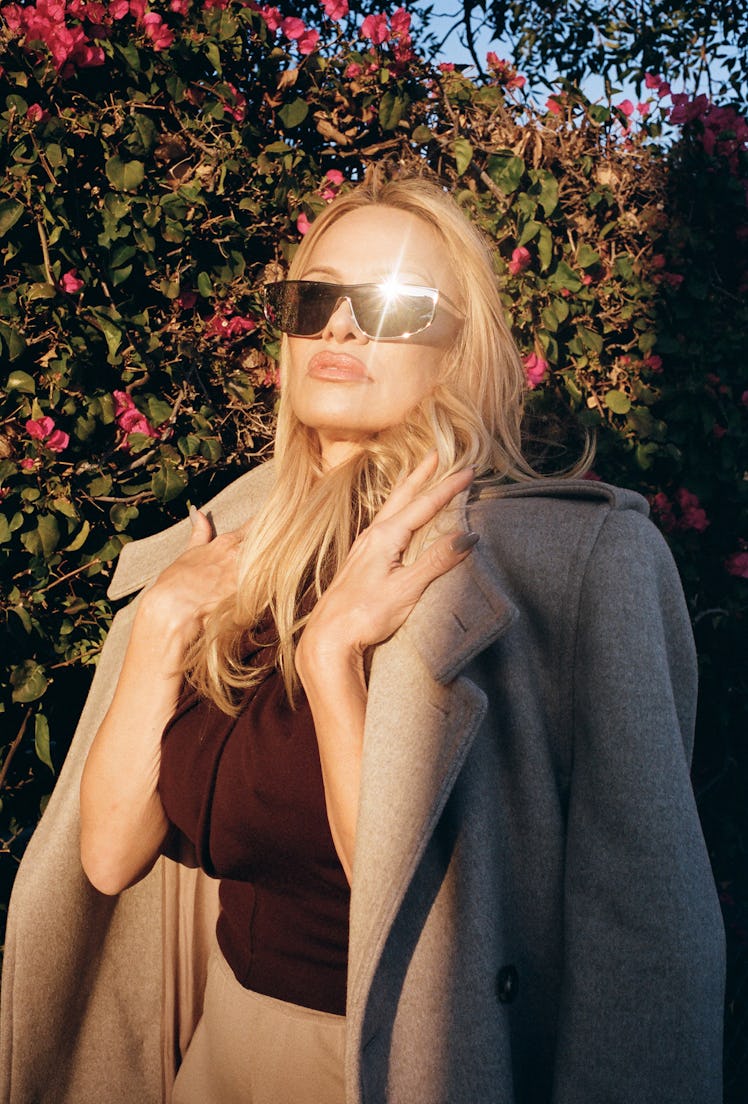 Pamela Anderson wears a Saint Laurent by Anthony Vaccarello coat, top, pants, and sunglasses.