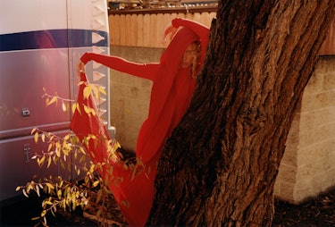 Raquel Zimmermann wears a red jumpsuit and scarf.