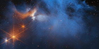 color image of a blue and orange cloud of gas in space, lit by a few bright orange stars on the left