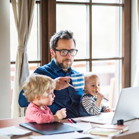 Middle aged man working at computer with two kids on his lap